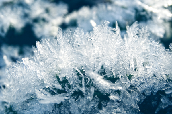 A macro shot of ice crystals on a dark blue green background